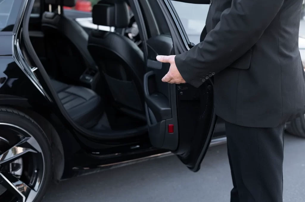 Professional chauffeur opening the door of a luxury limo for an Oakville airport transfer.